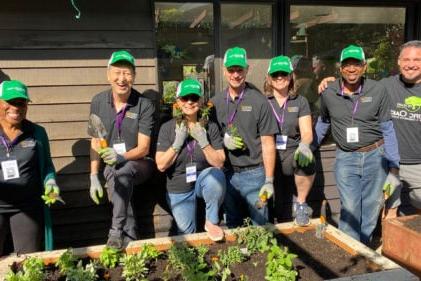 group of people smiling wearing green hats by a raised flower bed